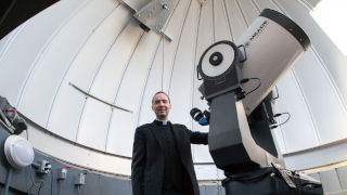 42081389_laracyx320 Photo of Father Laracy in front of a telescope
