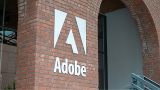 Adobe Building 320x180 Image of the brick outside of the Adobe Building, with the word Adobe and a white A logo on the wall.