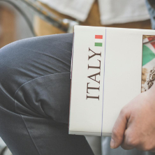 Charles and Joan Alberto Italian Studies Institute 222 Image of a male sitting holding an Italy textbook in a street.