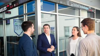 business students talking in front of trading room