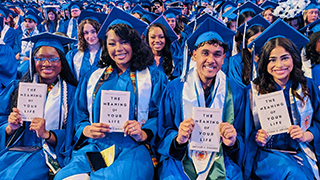 Graduate at Commencement holding a book.