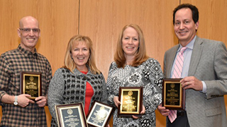 Teacher/Adjunct of the Year Four winners of the Teacher/Adjunct of the year award with their awards.