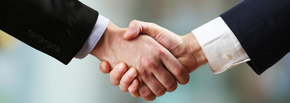 Image of two men in blazers shaking hands.