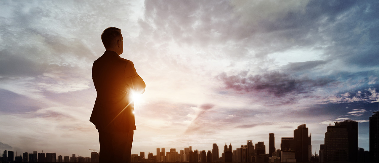 Character Moves the Mission A person in business attire looking out over the city at sunset.