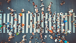 Many people walking across a crosswalk.
