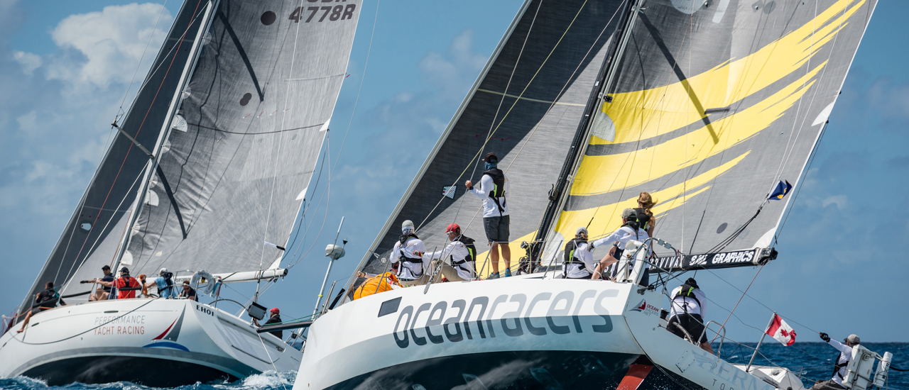 In Focus with Meg Reilly Two sailboats with their crews out on the ocean.