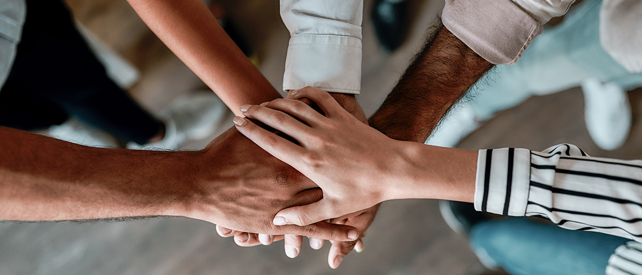 When Trust Is In Your Hands A group of people with their hands overlapping in the middle.