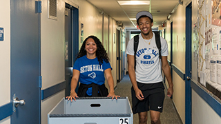 Students in hallway with a bin during move-in day. 