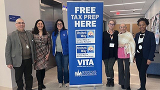 Tax lab members with sign that says "Free Tax Prep Here"