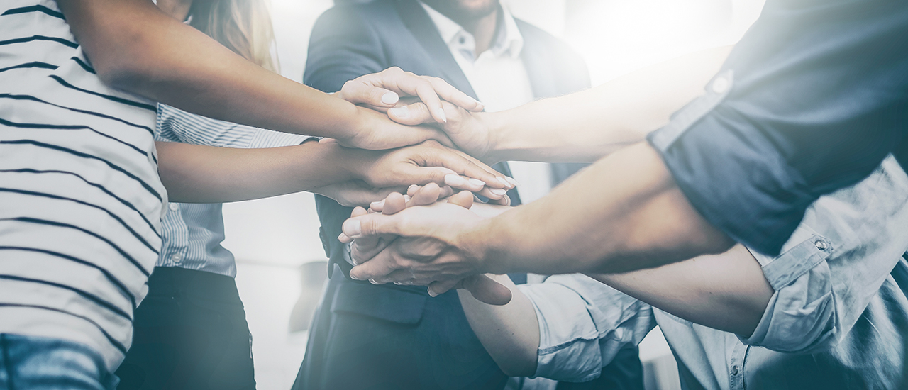 Teamwork in Leadership A team of people stacking their hands together.